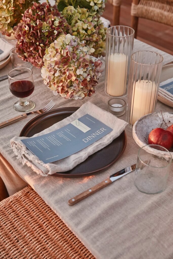 17 Inspiring Dinner Party Table Settings and Decoration Ideas Celebration table with pink and green hydrangeas, candles in ribbed glass holders, and a blue menu on a linen napkin.